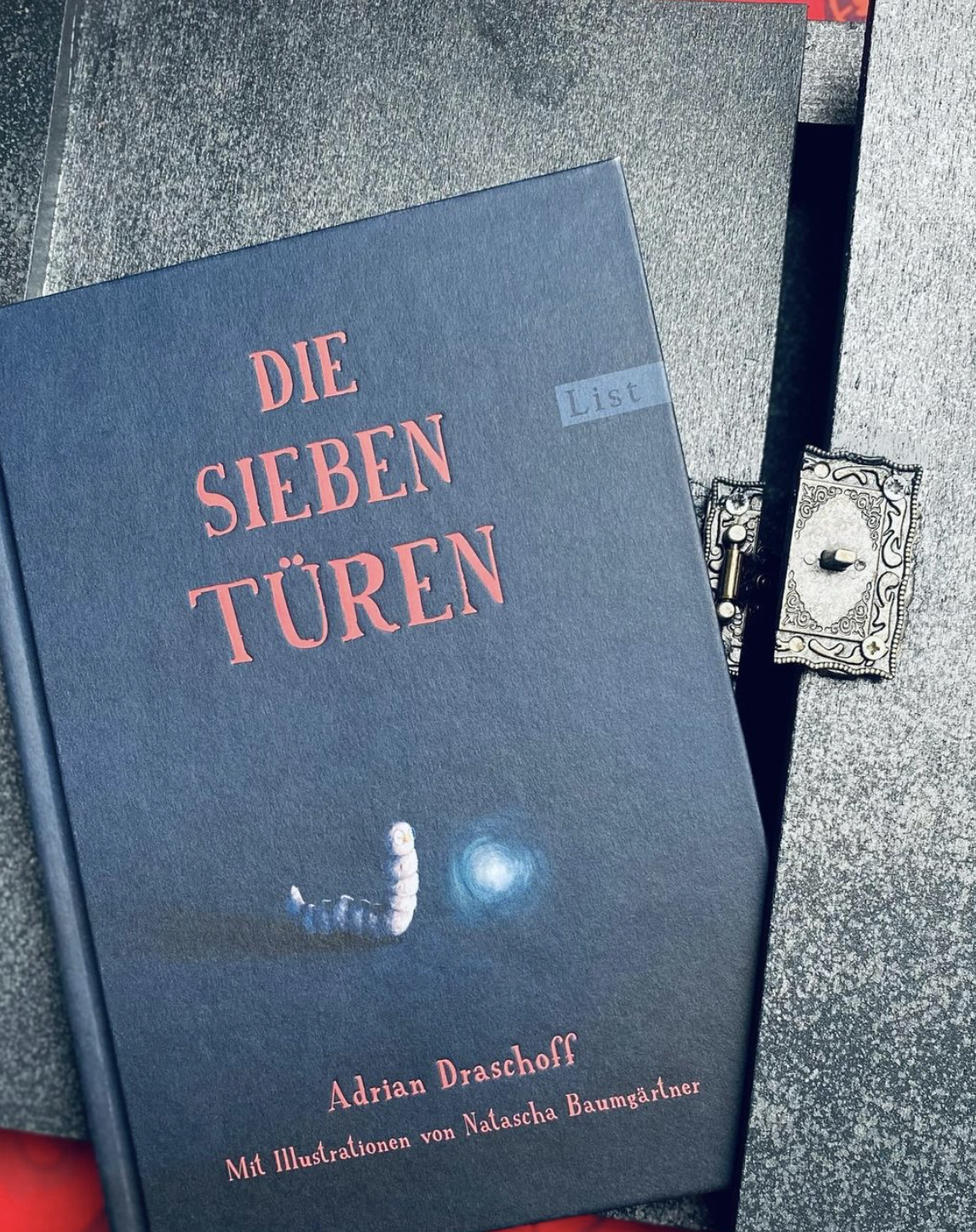 Ein schwarzes Buchcover mit einem Wurm. Die sieben Türen.